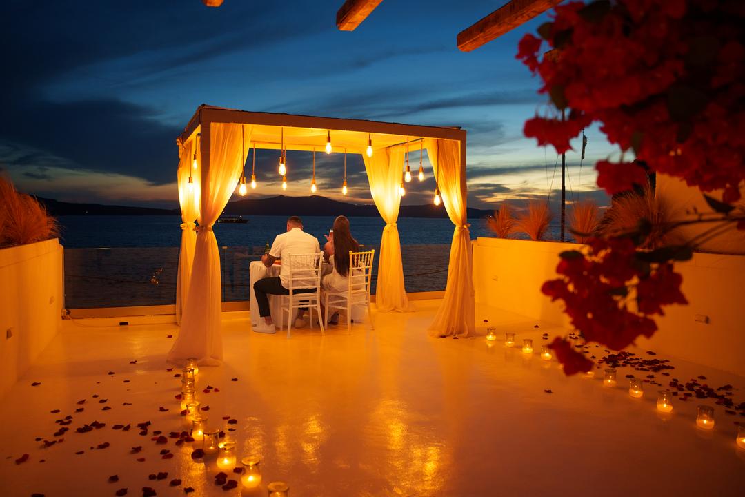 A canopied table glowing at dusk at the edge of the sea