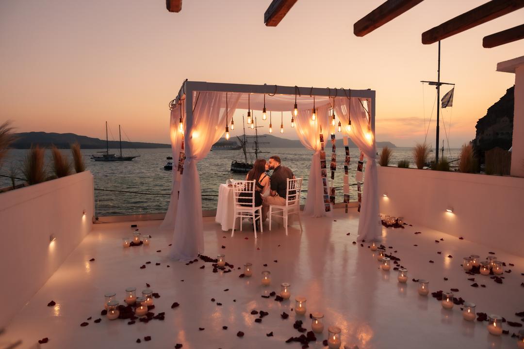 A draped dinner canopy at the water's edge as the evening turns gold