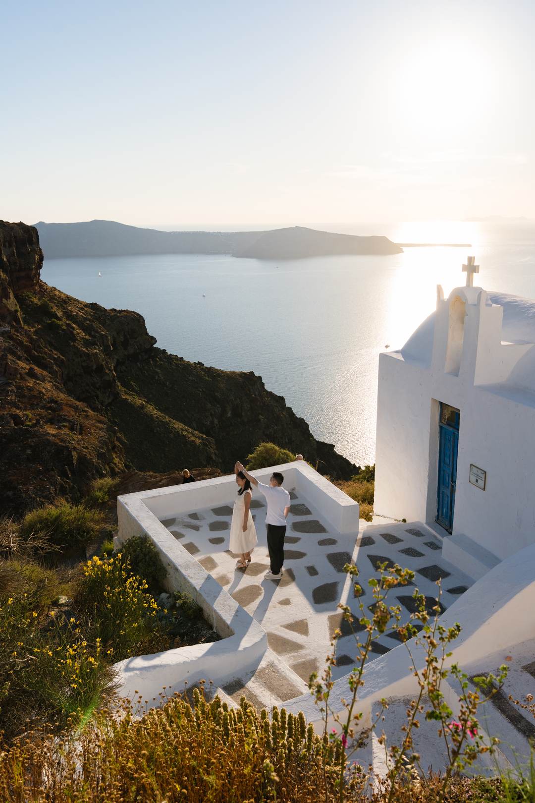 A couple at a whitewashed chapel high above the caldera