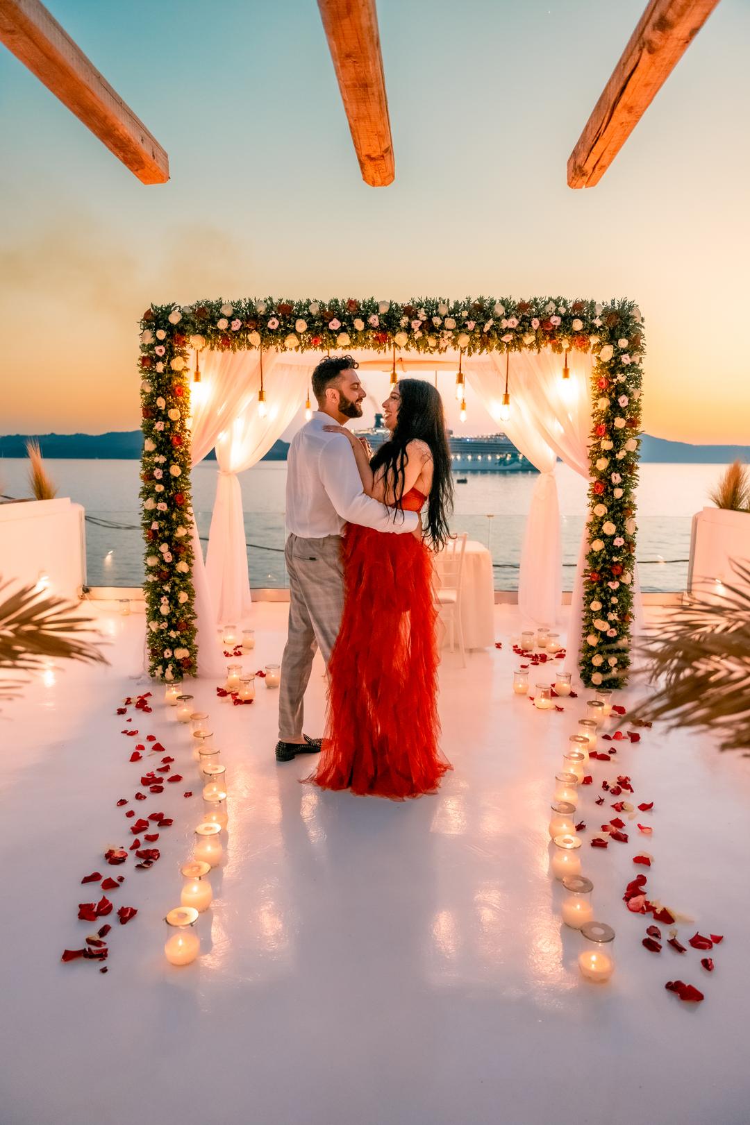 A couple beneath a lit floral arch after dark