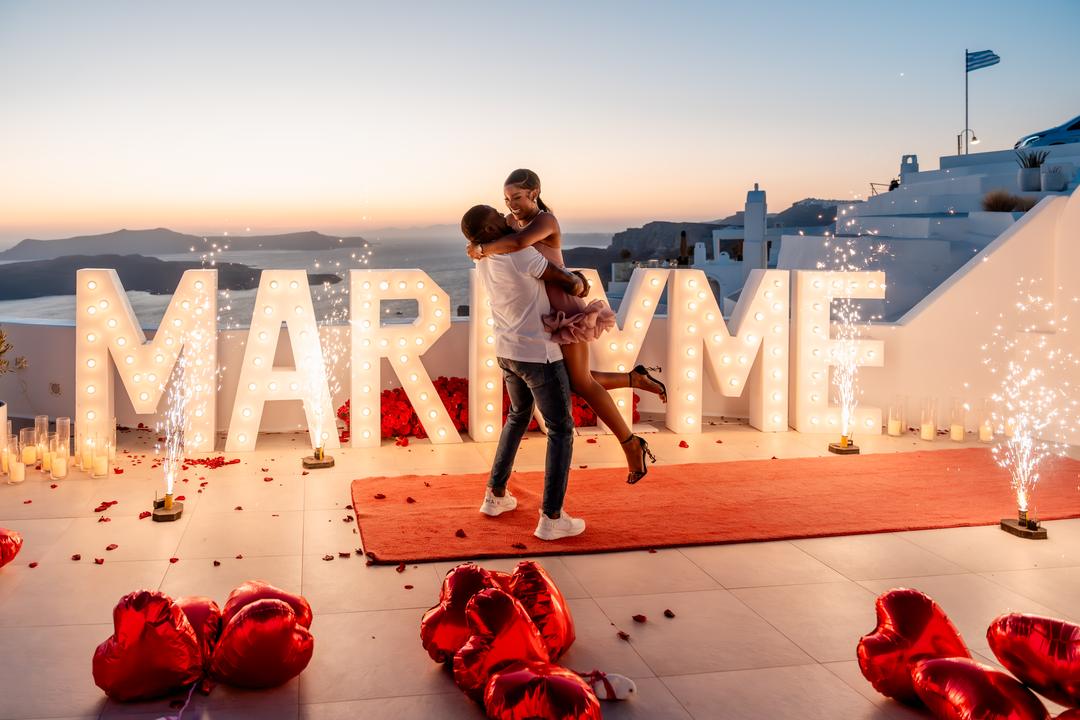 A joyful lift beside glowing Marry Me letters moments after the yes