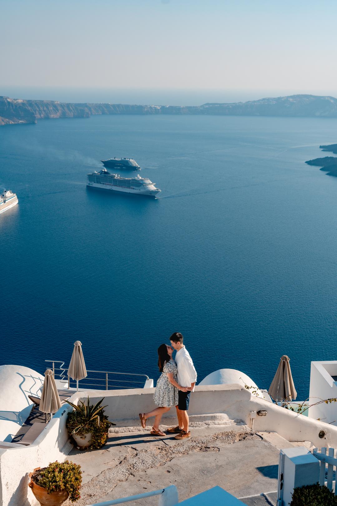 Aerial view of the Santorini caldera at golden hour, whitewashed villages along the cliff edge above the Aegean Sea
