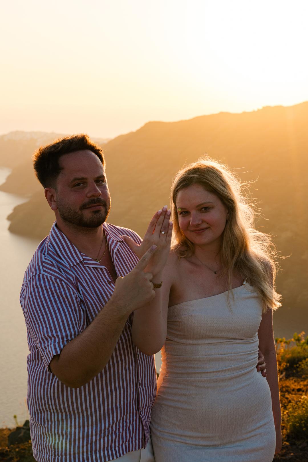 A woman turning her hand to show a new ring, warm evening light across both their faces