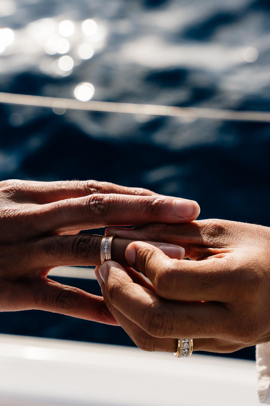 Two hands together over the water, both wearing new rings
