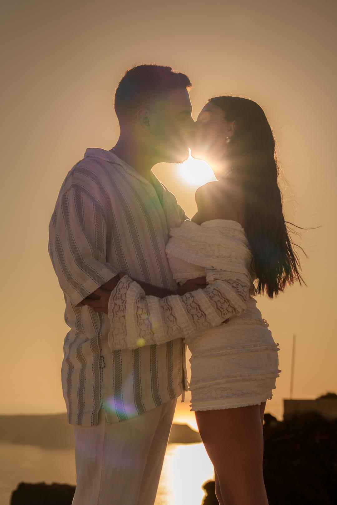 A couple embracing with the sun flaring directly between them at the end of the day