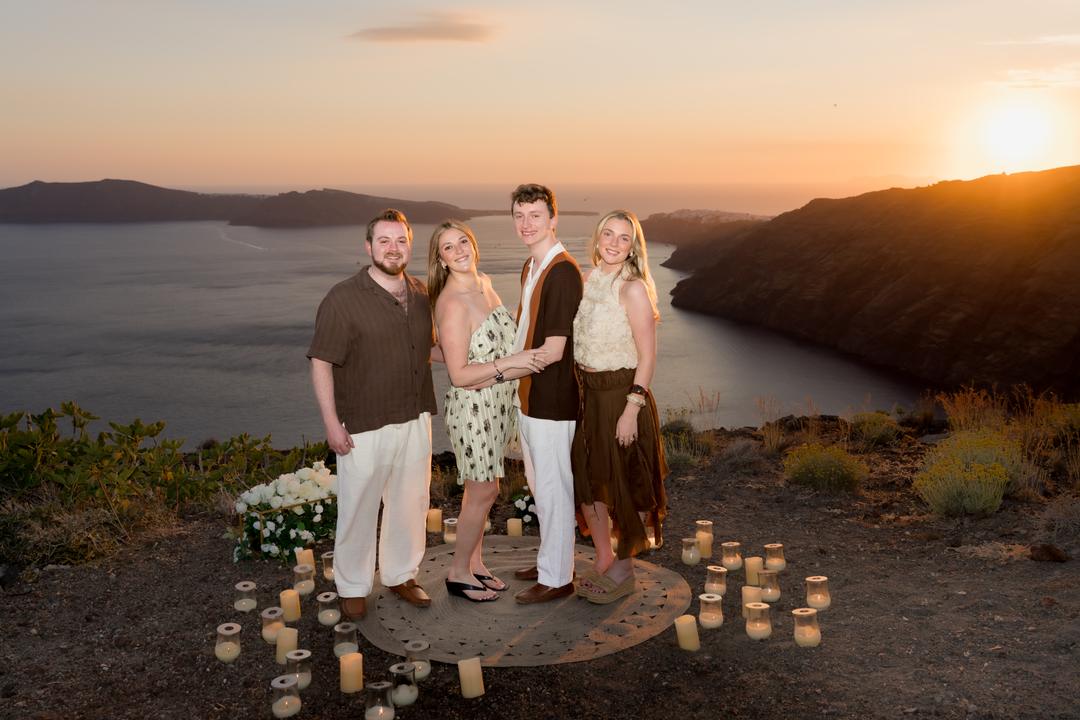 A low picnic table with cushions and candles set on a quiet ledge above the caldera at sunset