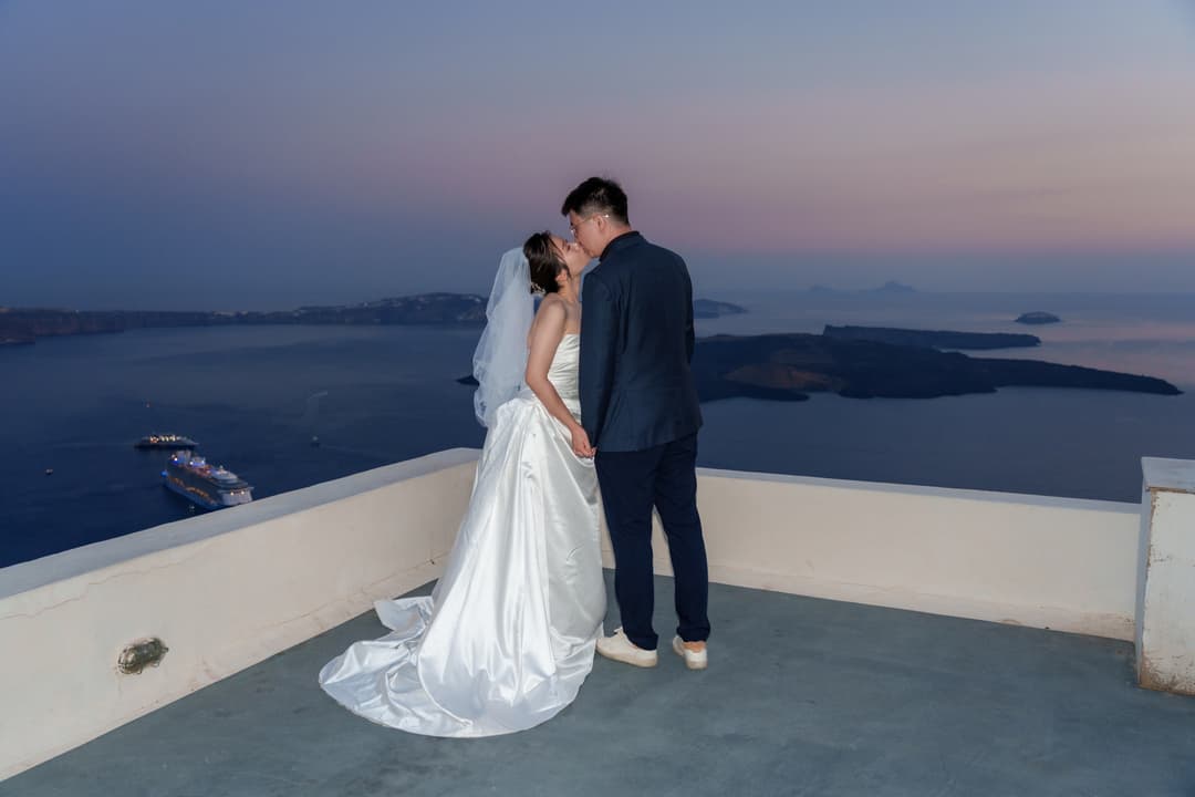 A couple kissing on a quiet terrace high over the caldera in the last violet of the afterglow